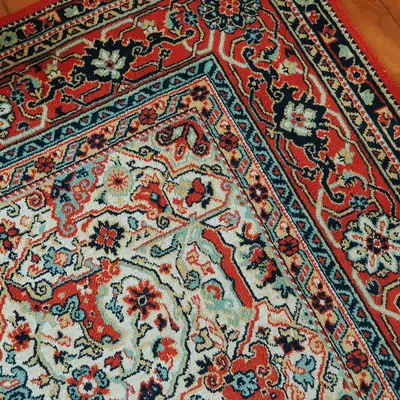 Ecke eines Orientteppichs mit roter und türkiser Blumenbordüre