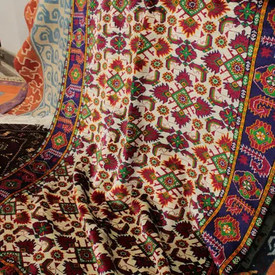 Teppich mit floralem Muster in Rot und Creme, über ein Möbel gelegt