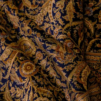 Detail eines dunkelblauen Teppichs mit goldenem Rankenmuster